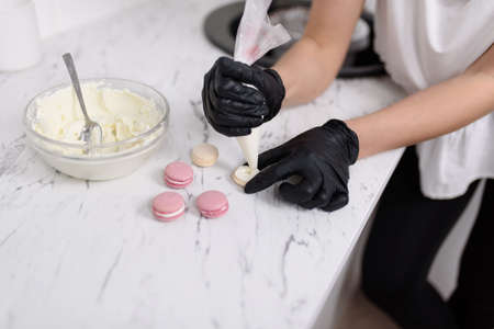 Womens hands apply cream to half of the almond cookies.Close-upの写真素材
