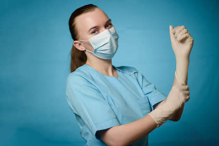 A doctor in a medical mask puts gloves on his handsの写真素材