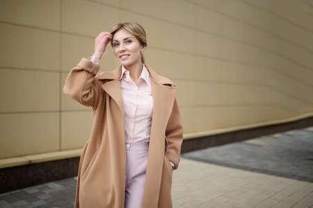 A businesswoman stands at the entrance to the office and straightens her hair.の写真素材