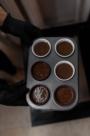 Womens hands put a tray of cakes in the oven to bake them