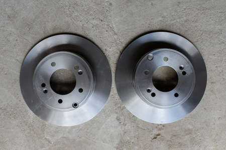 Two new brake discs are lying on the gray concrete floor.Top viewの写真素材