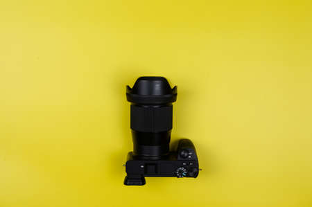 Black mirrorless camera with a lens on a yellow background.の写真素材