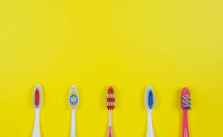 Colorful new toothbrushes on a yellow background in a row. Copy space.Top viewの写真素材