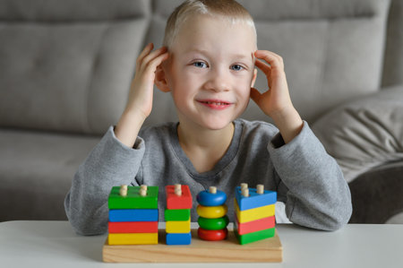 The child plays with an educational wooden toy and is glad that he folded it.
