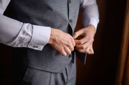A man fastens a button on his jacket, close-up.Morning preparation of the groom.の写真素材