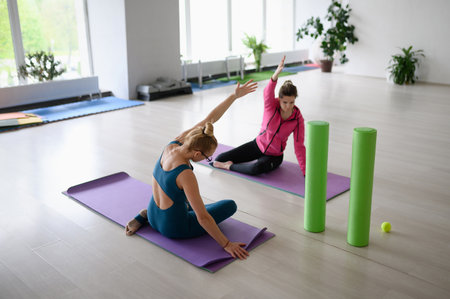 Pilates instructor and woman in sportswear in the gym perform body tilts.Rehabilitation after injury, posture correctionの写真素材