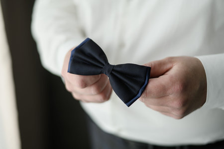 Black bow tie in the hands of the groom. Bow tie in the hands of a man. The concept of business...
