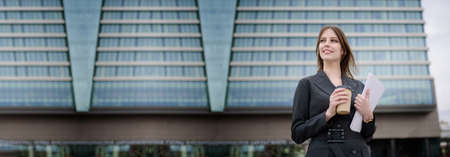 Women in business clothes stand in front of a business center with documents and coffee. Successful deal concept.Bannerの写真素材
