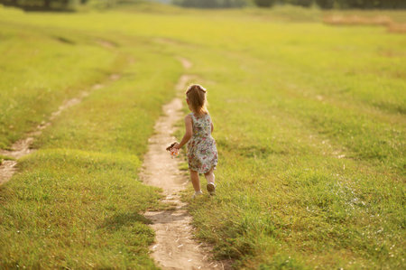 Portrait of a girl in a summer dress running across the field in summer. Concentration of children and nature.Copy spaceの写真素材
