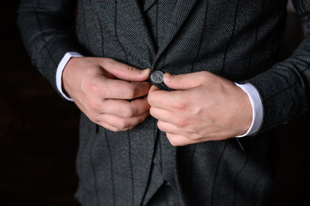 Portrait of a fashionable man buttoning a button on his jacket, close-up.Concept of mens...