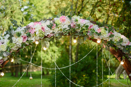 Wedding arch decorated with flower arrangement with light bulbs The area of the wedding ceremony in nature.の写真素材