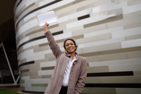 African american woman manager in business attire rejoices in a deal against the backdrop of a cityscape.Copy spaceの写真素材