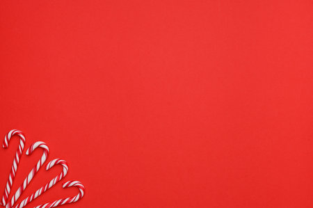 Layout of four white canes with red stripes, sweet Christmas candies on a red background. The concept of traditional Christmas sweets. top view. copyspace.の写真素材