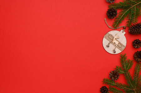 Christmas, New Year composition. Layout of fir branches, cones, wooden toys on a red background.Flat lay, top view, copy space. Concept of christmas, winter, new year.Christmas wallpaper.の写真素材
