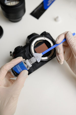 Hands holding sensor cleaning swab and applying a special cleaner to clean the camera sensor. Cleaning and maintaining the mirrorless camera sensor.Care for professional photographic equipment.の写真素材