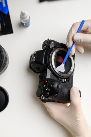 Cleaning with a professional swab to clean the sensor matrix from dust and dirt. Cleaning and caring for the mirrorless camera sensor. The concept of care for professional photographic equipment.の写真素材