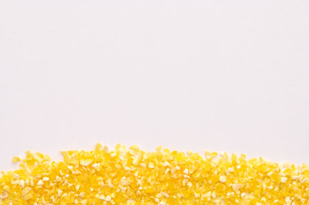 Macro photo of dry yellow corn porridge on a white background. Healthy, delicious food, source of amino acids, minerals, vitamins, natural antioxidantの写真素材