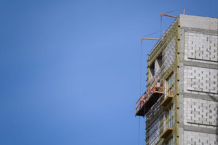 Workers sheathe the outer walls of the building with insulation.Insulation of the facade of the...