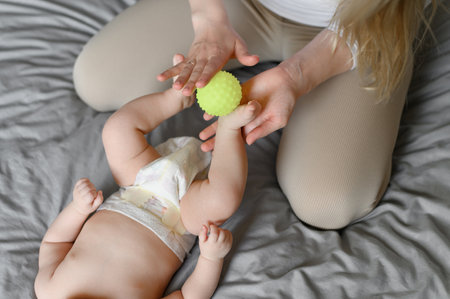 Mom massages the childs legs with a massage ball. Children massage. Nanny, maternity leave, massage therapist, conceptの写真素材