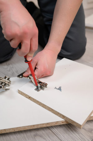 Furniture assembly. The worker inserts the loop and tightens it with a screwdriver. Adjustment of fittings, door hinges.の写真素材