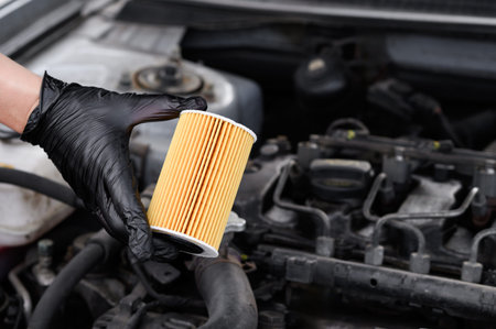 Auto mechanic holds an oil filter for diesel cars in his hands against background of engine...