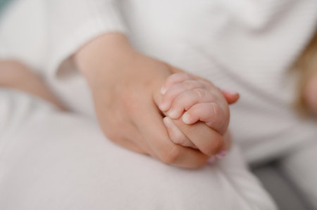 Mom holds infant hand in her palm, close-up. Newborn, motherhood, family, birth concept, maternity leave. Mother care for newborn baby, mother love.の写真素材
