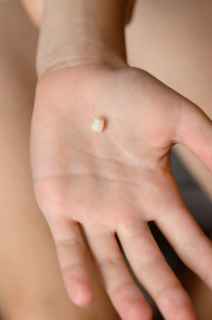Child holds fallen baby tooth in his palm, close-up. Baby teeth are replaced by permanent ones....