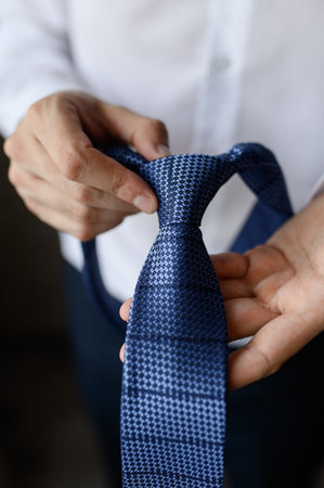 Man holding stylish blue tie in hands, close-up. Business wear concept, mens style, grooms morning....