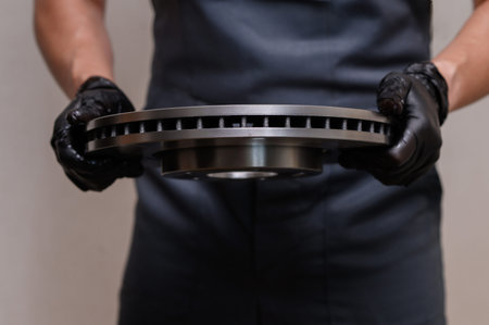 Brake technician prepares disc for replacement and inspection. Workshop technician carefully...