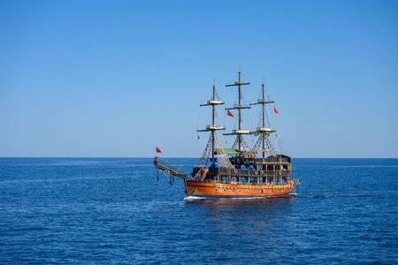 Alanya, Turkey, June 24, 2025. Wooden sailing ship glides across sparkling blue waters. Graceful vessel sails seas with its crew and passengers enjoying journey. Concept of sea travel.のeditorial素材