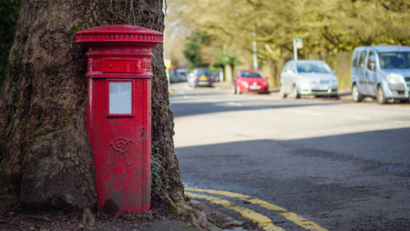 Photo of a 120-year old traditional British post box being swallowed up by a treeの写真素材