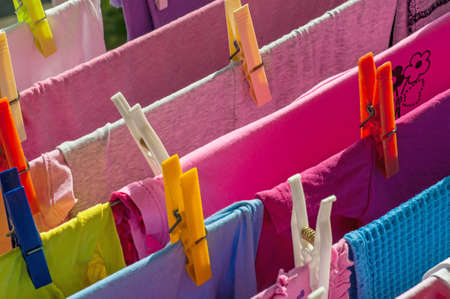 Mixed clean laundry pinned with colourful clothespinsの写真素材