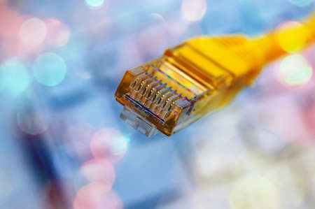 Macro of a yellow network cable in front of a computer keyboardの写真素材
