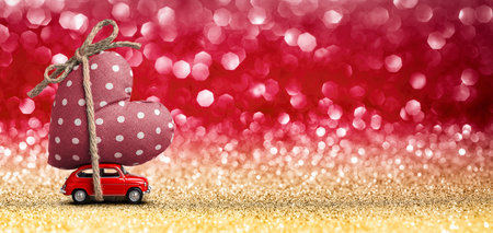 Valentines Day Incoming - Miniature Red Car Carrying Heart and Glitter Backgroundの写真素材