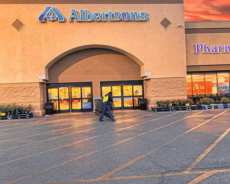 Albertsons grocery store early in the morning showing dramatic sky and worker pushing shopping carts.のeditorial素材