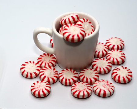 Antique copper vessel with pepperming candy on a white background.