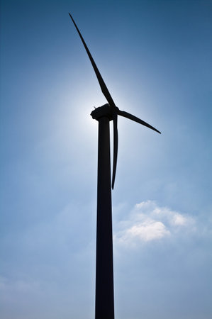 wind turbine in the backlight of the sun against blue sky