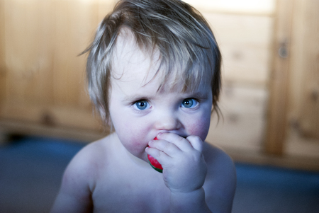 blue eyes baby eating red ballの写真素材