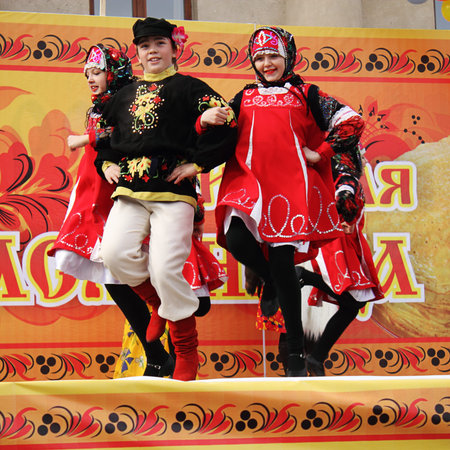 cheerful girls and boy dancing in  Russian Maslenitsa
