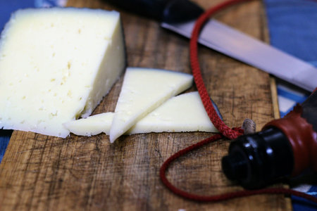 Manchego cheese cut on a wooden board. Accompanied by a wine from Rioja.