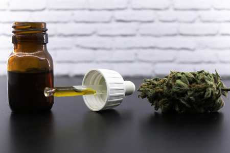 Medicinal marijuana buds and cannabis seeds on a black table and with a white backgroundの写真素材