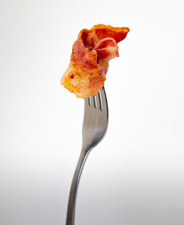 Crispy bacon on a fork isolated on white background, close upの写真素材
