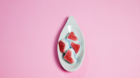 Colorful candies in the shape of hearts on a pink backgroundの写真素材