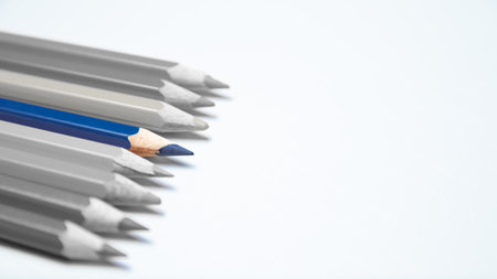 Gray crayons, in the middle one blue crayon that stands out, on a white backgroundの写真素材