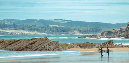 Couple of surfers walking on the beach. Going to do some surfingの写真素材