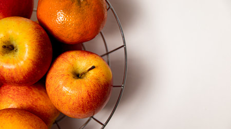 A bowl of apples and tangerines on a white backgroundの写真素材