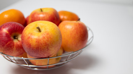 A bowl of apples and tangerines on a white backgroundの写真素材