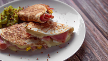 Tortilla with ham, cheese and guacamole on wooden backgroundの写真素材