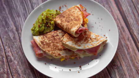 Tortilla with ham, cheese and guacamole on wooden backgroundの写真素材