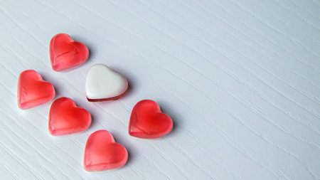 Red and white heart-shaped candies on a white wooden background